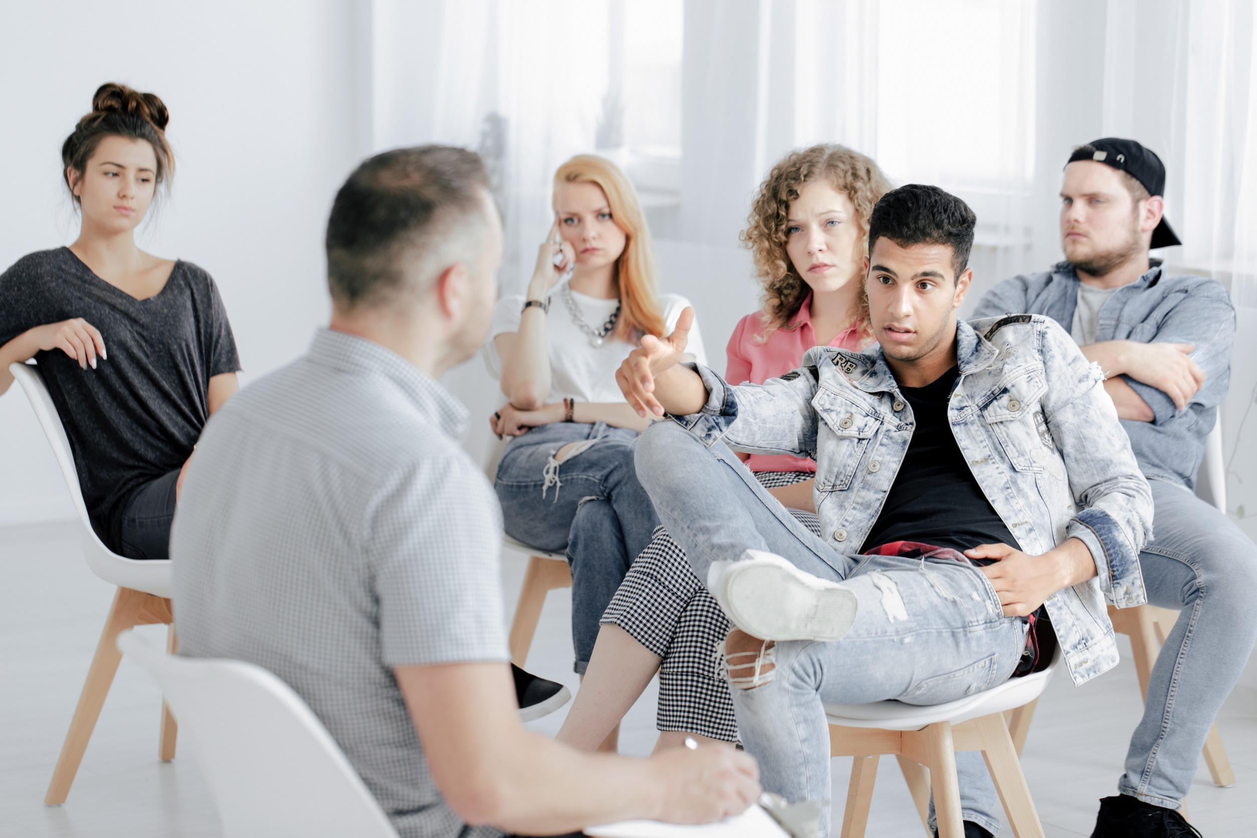 grupo de jovenes sentados ante psicologo